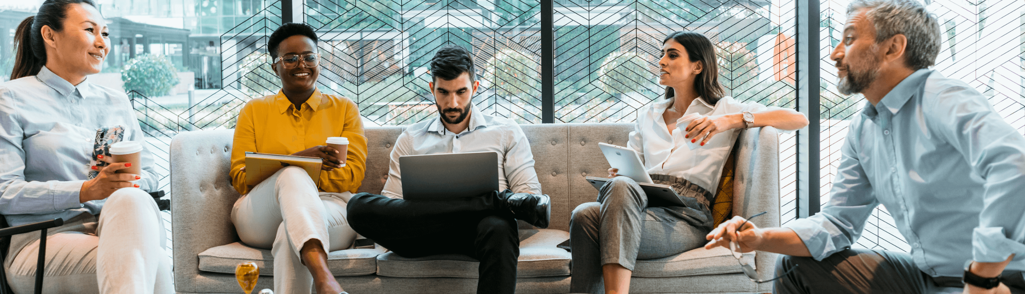 Employees drinking sitting, chatting and working on their computers