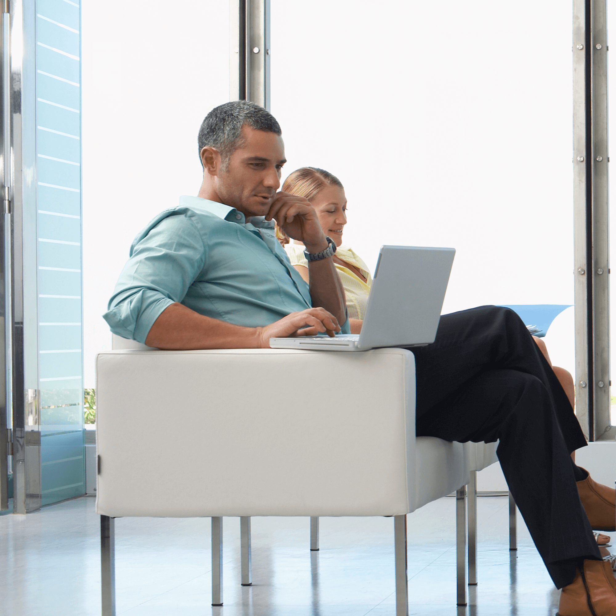 Person sitting on a chair looking at their laptop sitting on the armrest