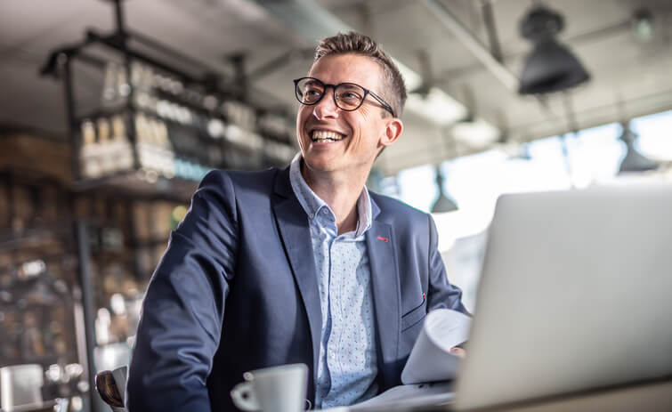 Person in a blue suit sitting at a desk and smiling