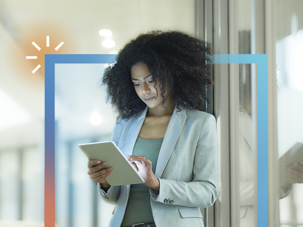 Woman standing in an office with a tablet.